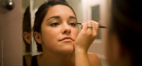 Cute Girl Looking in Mirror and Applying Makeup